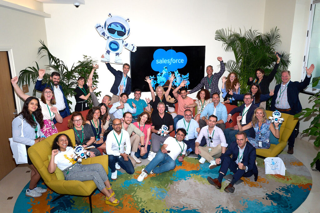 Photo de groupe en entreprise, les personnes présentes sur la photo sont toutes heureuses et l'exprime par leur sourires radieux.